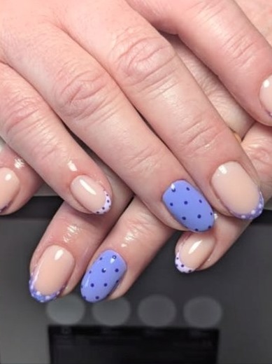 Nude nails with lilac polka-dot tips and two lilac accent nails